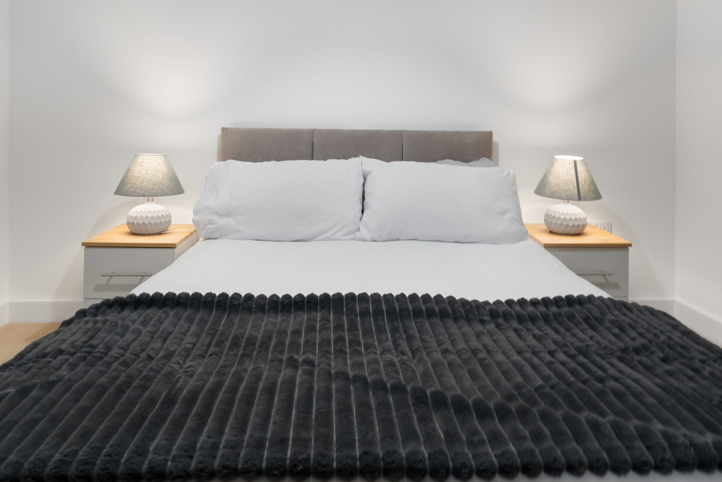 Double bed with grey headboard and bedside lamps