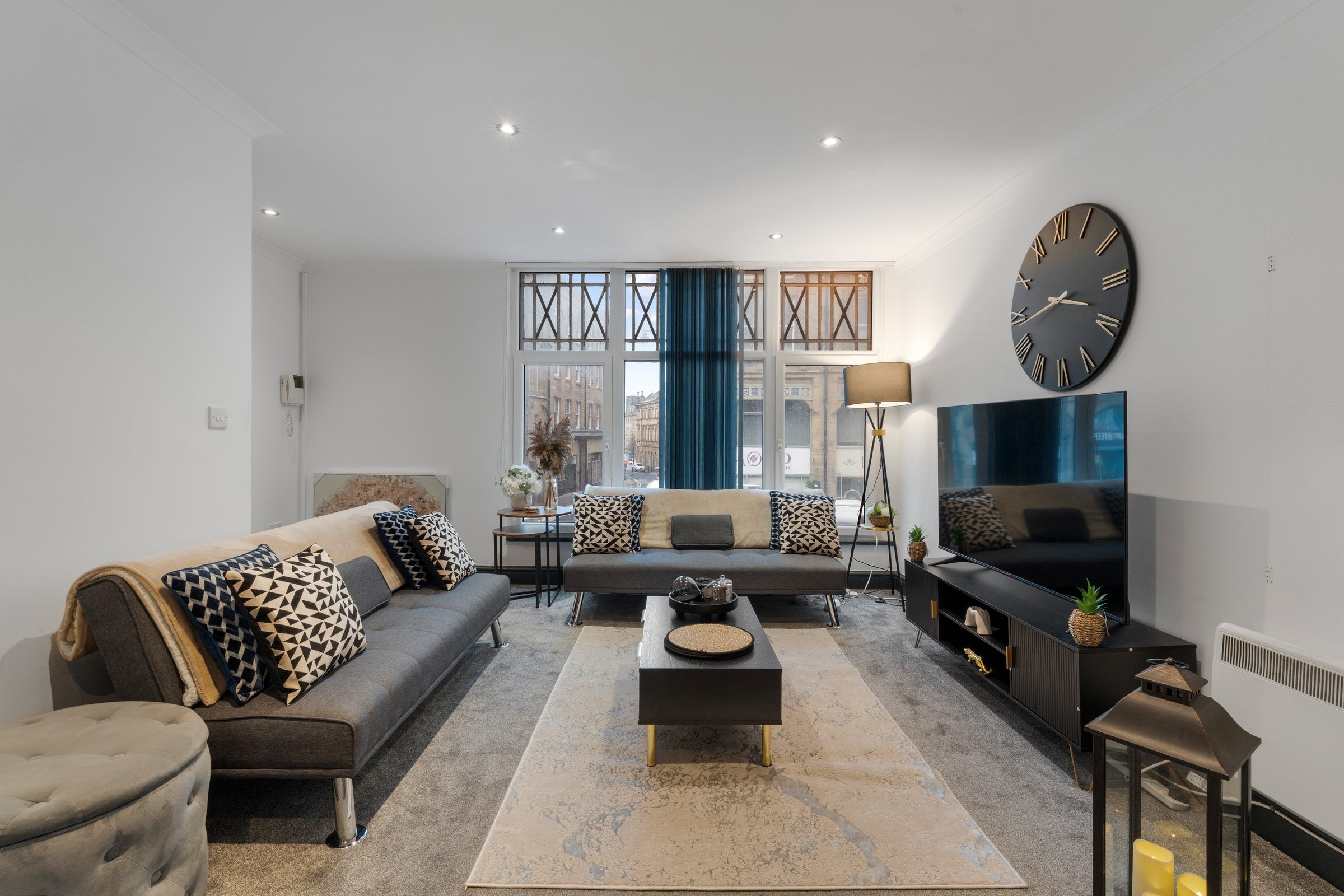 Living room with grey sofa, rug, TV unit and large wall clock