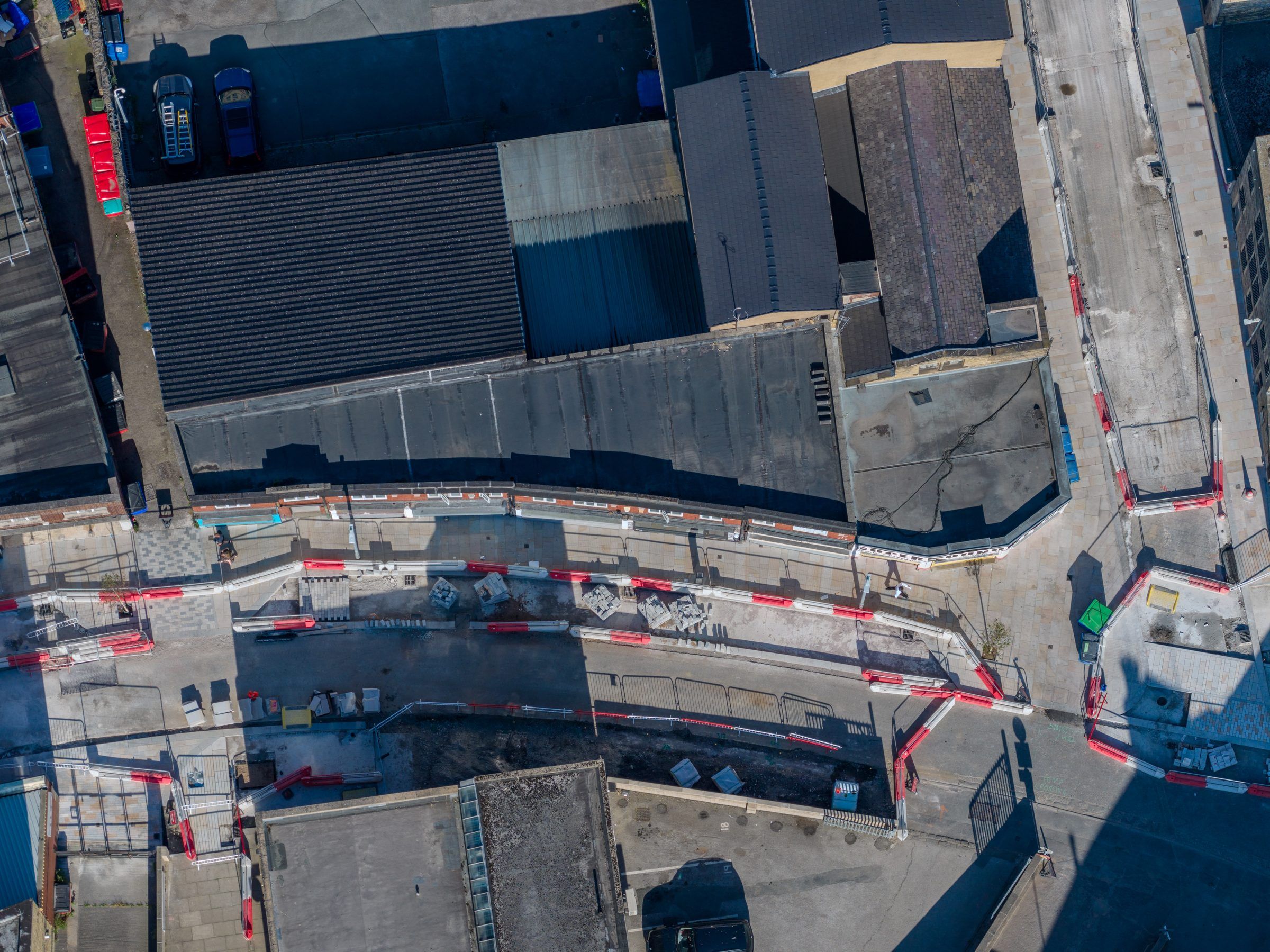 Top-down view of barriers along a street beside large roofs