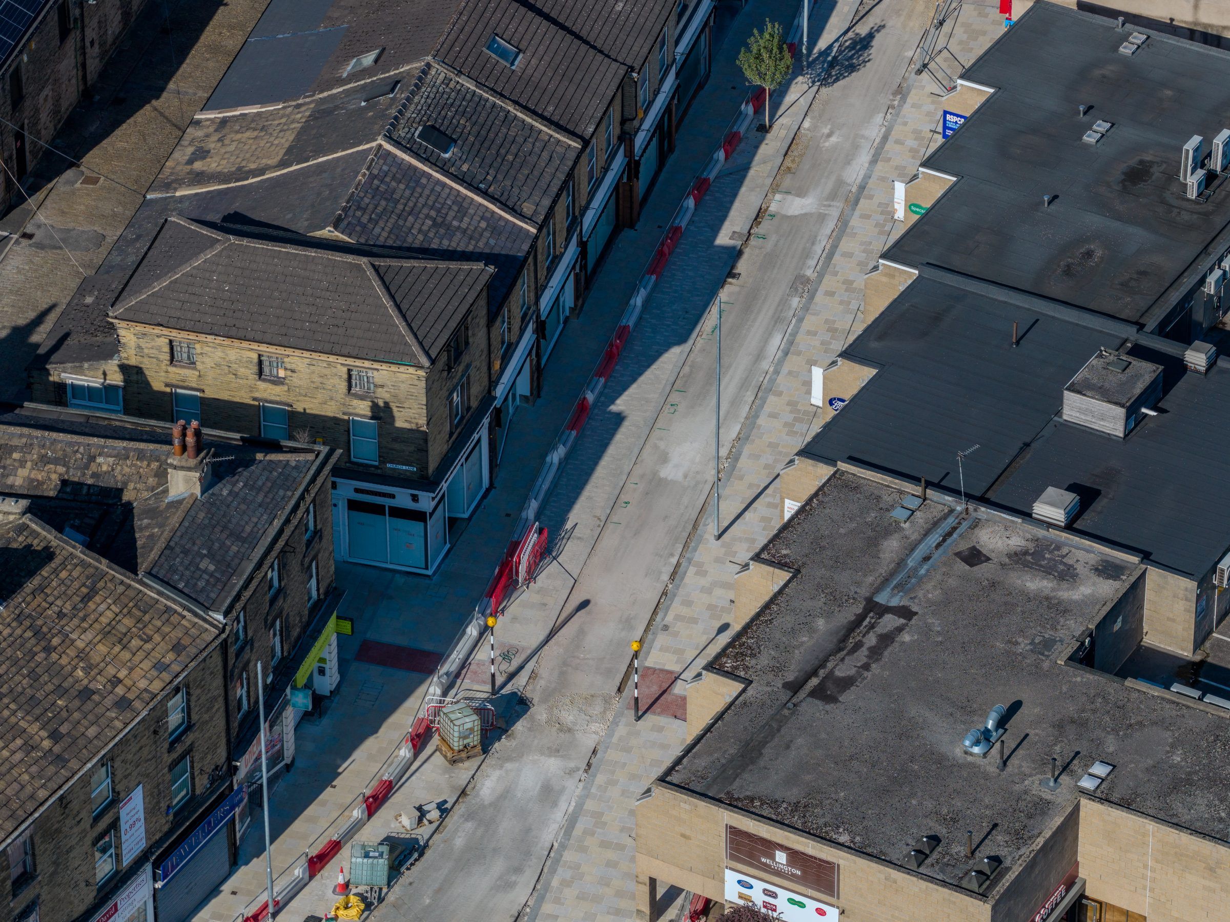 Aerial along a resurfaced street lined with stone buildings