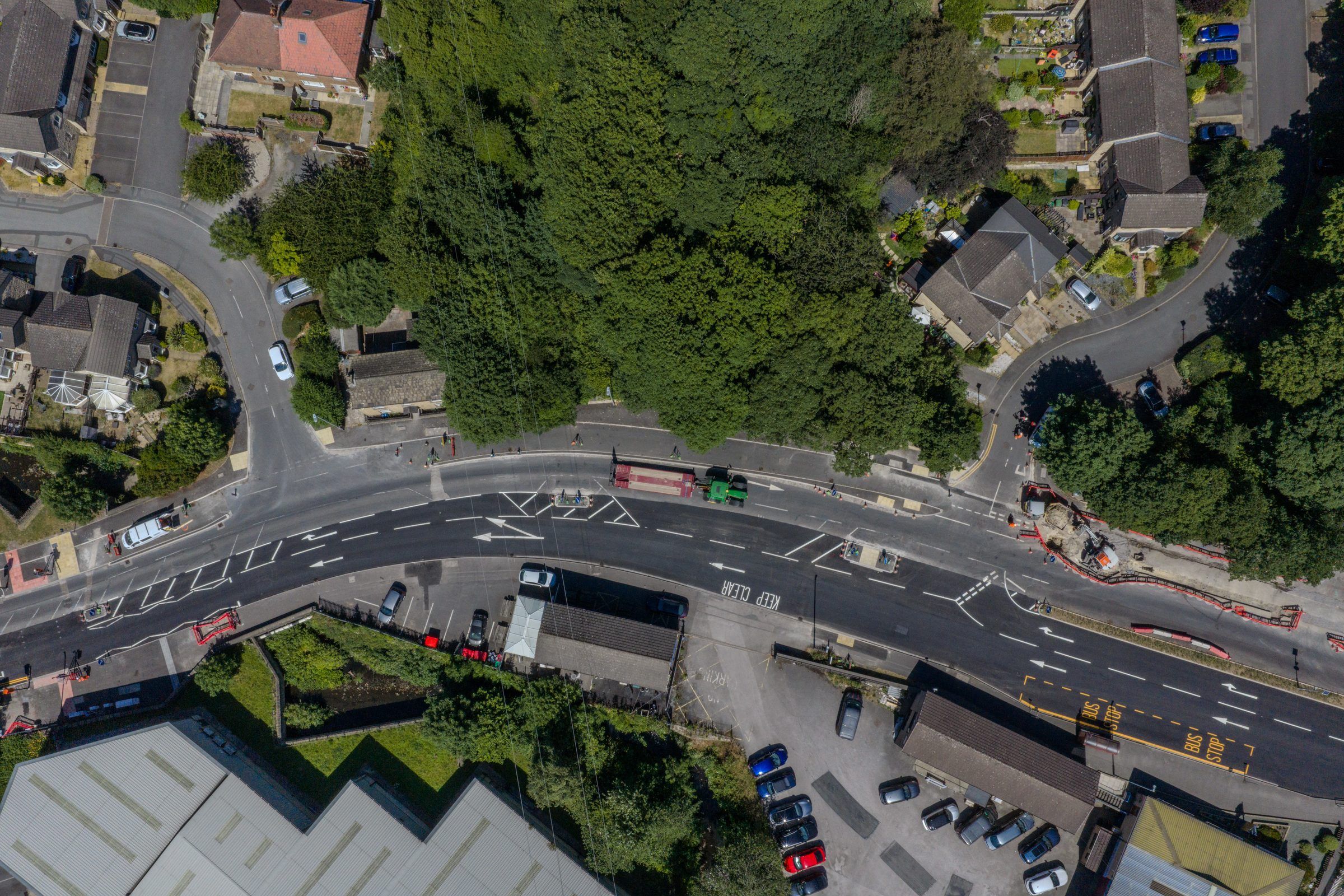 Aerial of a road curving past houses and woodland