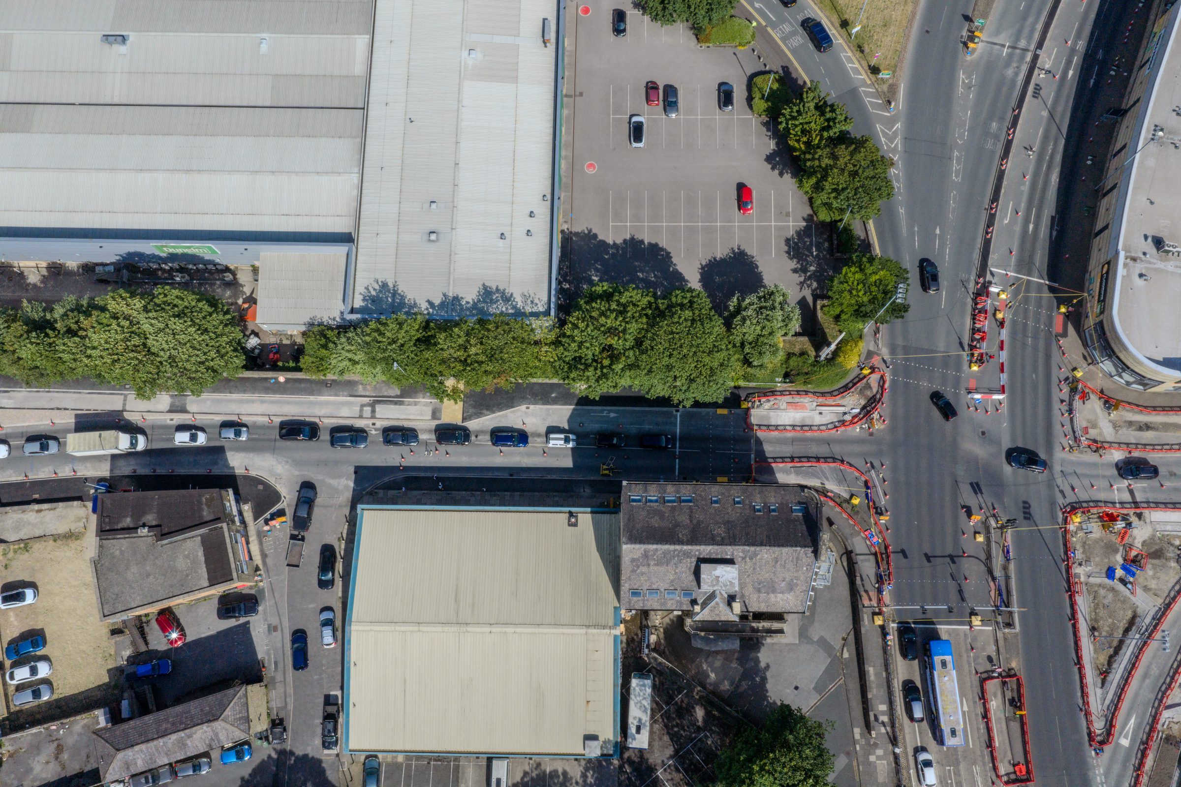 Top-down view of warehouses, a tree line and a main road